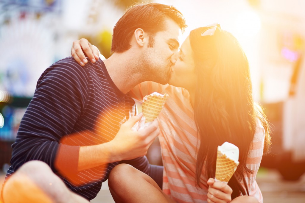 romantic couple kissing while holding ice cream